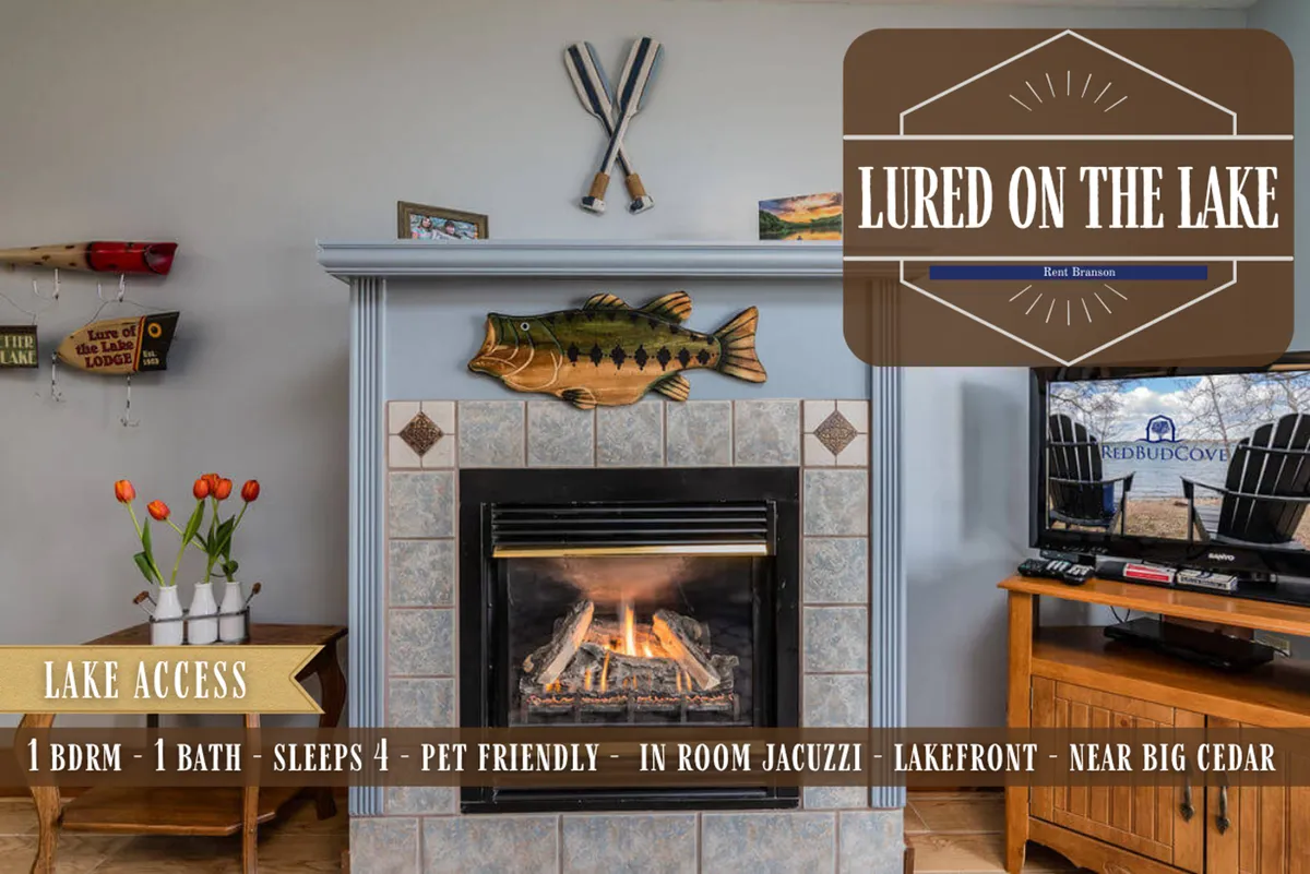 A warm, inviting living area featuring a seasonal propane fireplace, whimsical fish decor, and a sign pointing to lake access. The scene suggests a cozy gathering spot with nods to the lakeside setting and opportunities for relaxation by the fire.