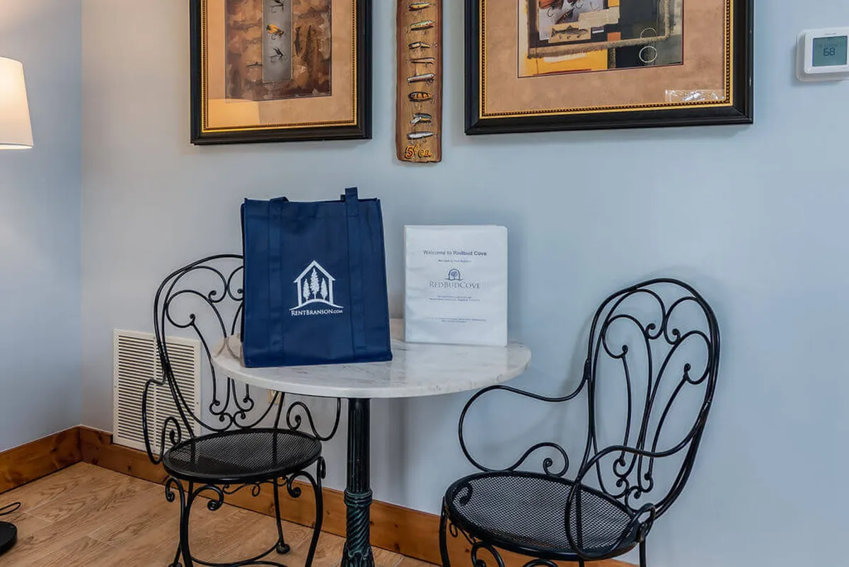 A corner of the suite with a small round table, two ornate chairs, and a welcome bag, complemented by decorative wall art. The area is well-lit, inviting, and offers a spot for relaxation or enjoying a morning coffee with your dog nearby.